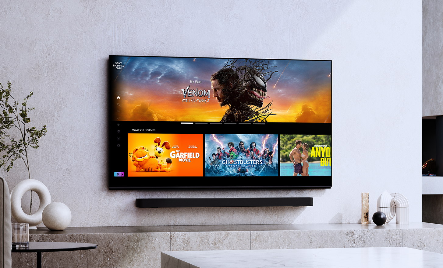 Un televisor que muestra los títulos de películas seleccionadas “Venom: El último baile”, “Garfield: Fuera de casa”, “Ghostbusters: apocalipsis fantasma” y “Con todos menos contigo”, ambientado en una sala de estar moderna.